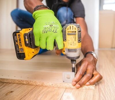 Man using a power drill for home improvement on a wooden floor with precision.
