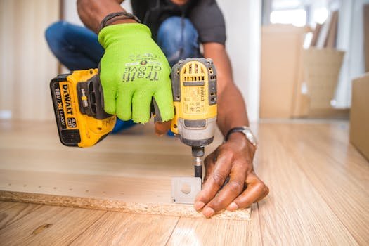 pexels-photo-1249611-1249611 Man using a power drill for home improvement on a wooden floor with precision.