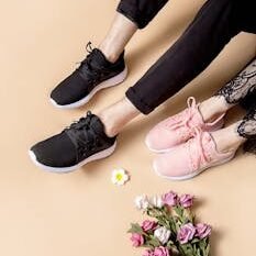 Pair of black and pink sneakers beside a bouquet of colorful flowers on a neutral background.